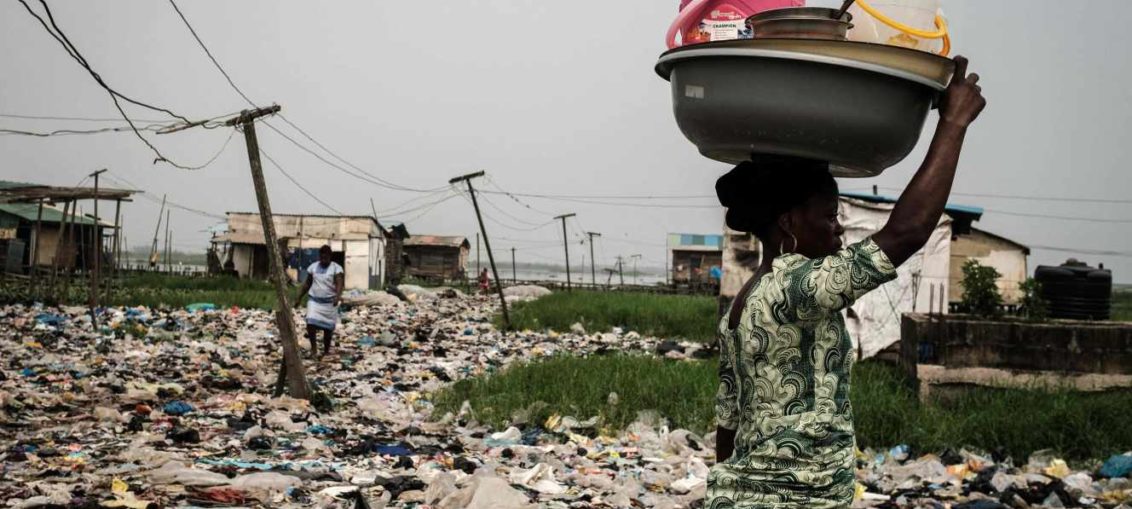 Une femme marche sur le sol jonché de déchets de plastique, dans le quartier de Mosafejo, à Lagos (Nigeria), en février 2019.