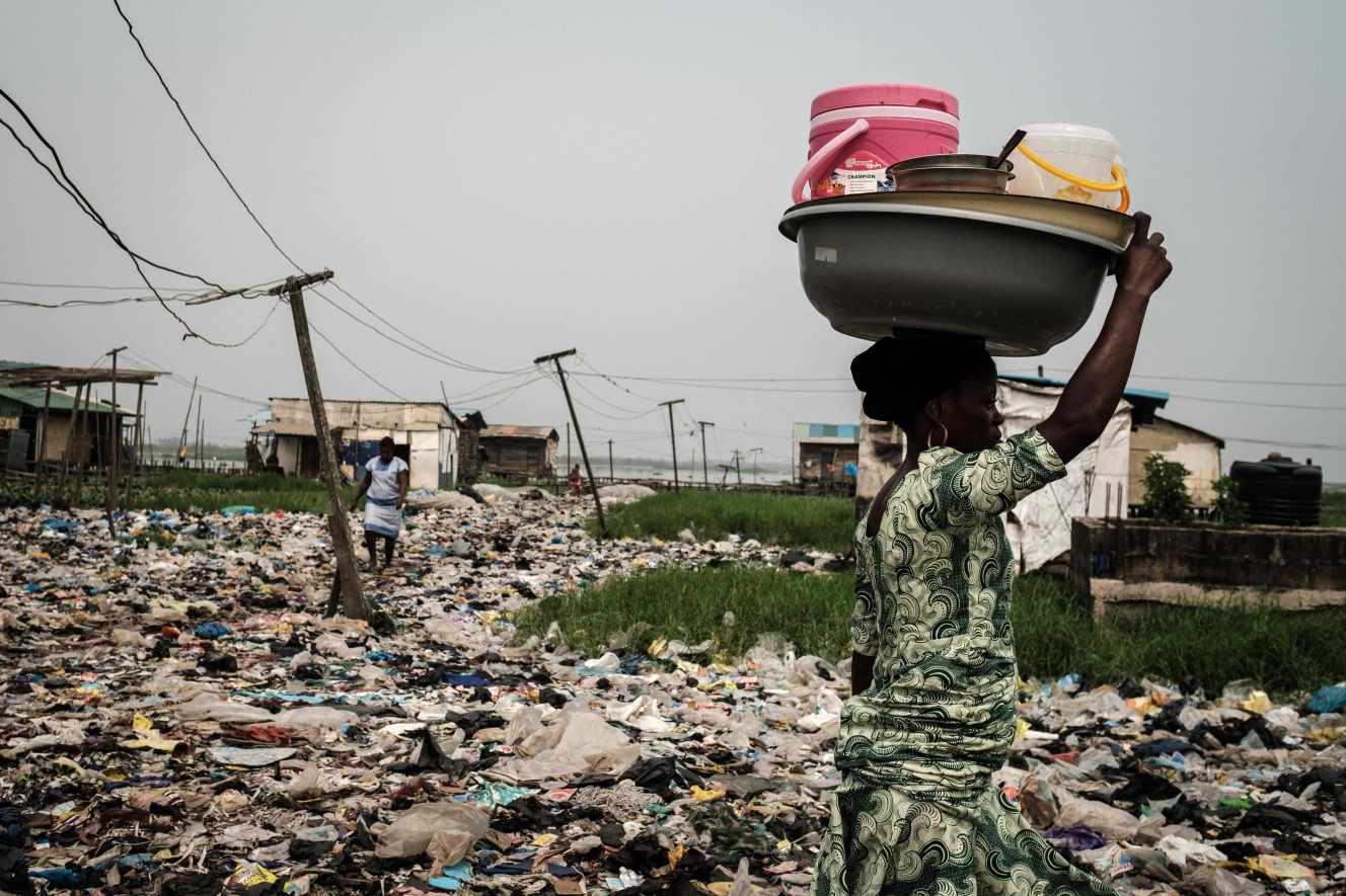 Une femme marche sur le sol jonché de déchets de plastique, dans le quartier de Mosafejo, à Lagos (Nigeria), en février 2019.